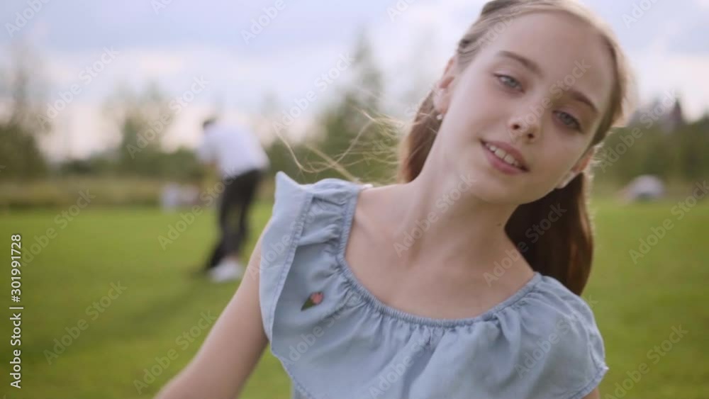 Charming long-haired 10 years old girl in a blue dress circling in the dance in a city park in the summer. Slow motion, close-up. Moscow Kremlin in defocus on the background. cloudy day Charming long-haired 10 years old girl in a blue dress circling in the dance in a city park in the summer. Slow motion, close-up. Moscow Kremlin in defocus on the background. cloudy day