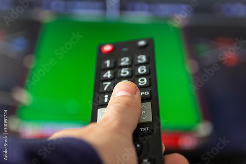 Man watching TV set and using remote control.