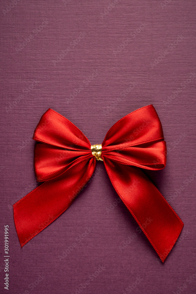 Gift red bow on vertical textured purple background Gift red bow on vertical textured purple background