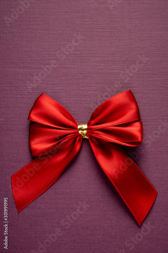 Gift red bow on vertical textured purple background