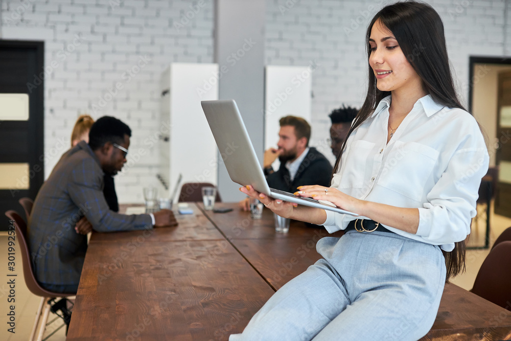 Attractive woman using laptop in her workplace, portrait of woman in white shirt holding laptop Attractive woman using laptop in her workplace, portrait of woman in white shirt holding laptop