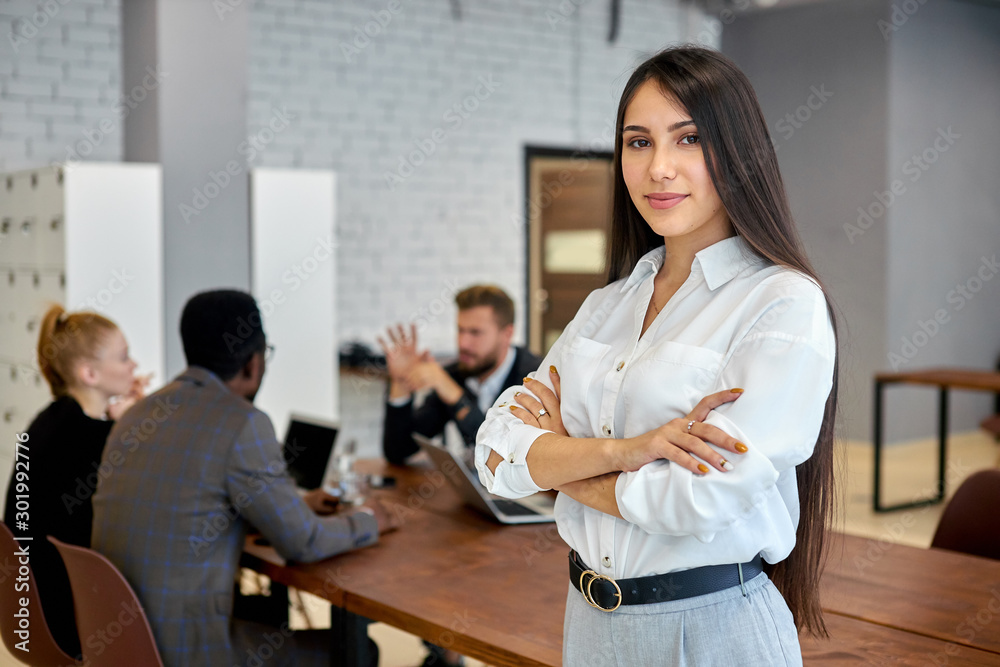 Obraz premium Personable and confident young woman brunette with long hair look at camera. Businesswoman in white shirt posing in office