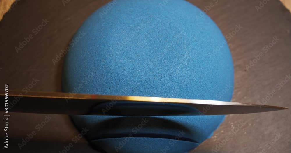Blue kinetic sand in a round shape is cut by a sharp knife