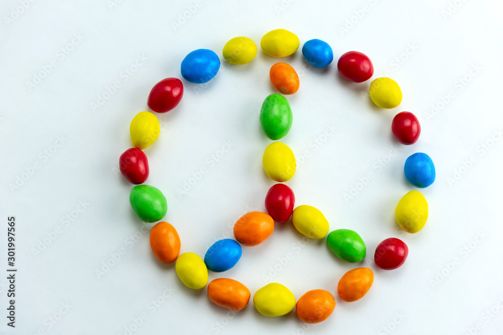 peace sign made from bright multicolored candies top view flat lay on a white background