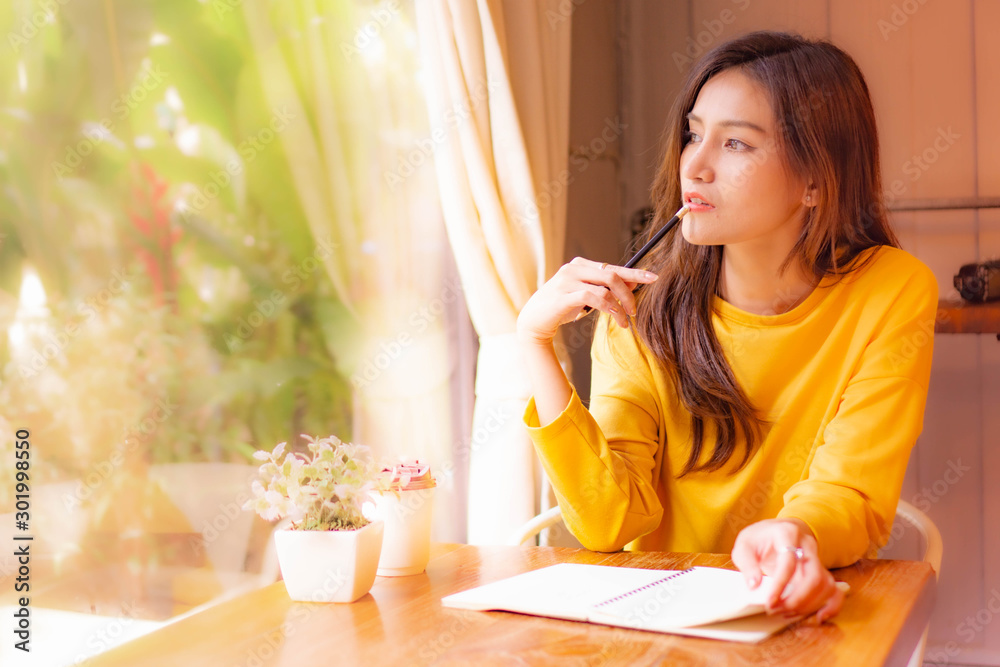 Asian beautiful Woman in yellow cloth siting in cafe thinking about work Asian beautiful Woman in yellow cloth siting in cafe thinking about work