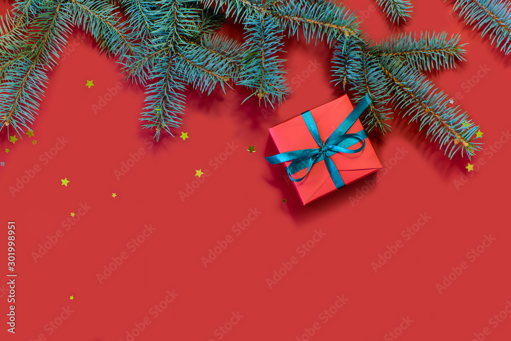 Image of beautiful red gift boxes and spruce branches on a red background.