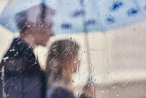 young couple under an umbrella. man and woman in the rain. double exposure. drops on glass © Olek