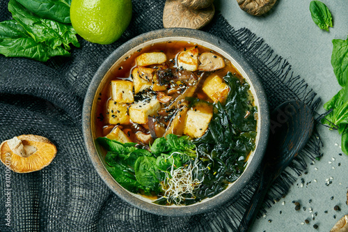 Fresh vegetarian miso soup with shiitake mushrooms, tofu cheese and seaweed on a gray cloth. Healthy, balanced food. Top view. Copy space