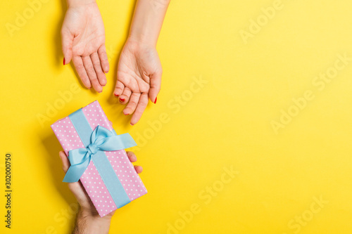 Top view of couple giving and receiving a gift on colorful background. Close up of romantic concept