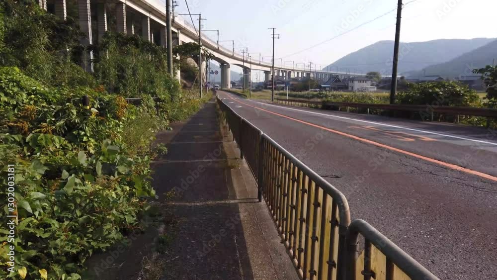 Rural Japan, walking POV shot down country highway with train overpass in the background