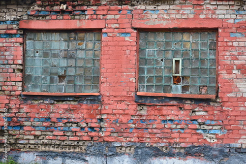 Old red brick wall. Shabby ancient wall of house with broken windows.