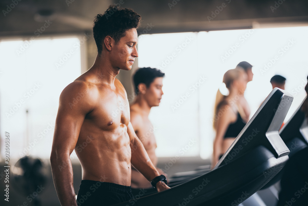 handsome man running on treadmill in fitness gym