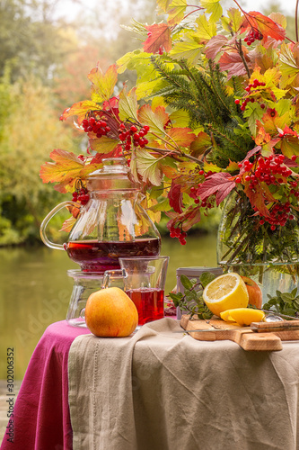 Autumn. A table set on the banks of the lake decorated with a bouquet of autumn leaves. Tea party. fruit teas with lemon, apples . photo