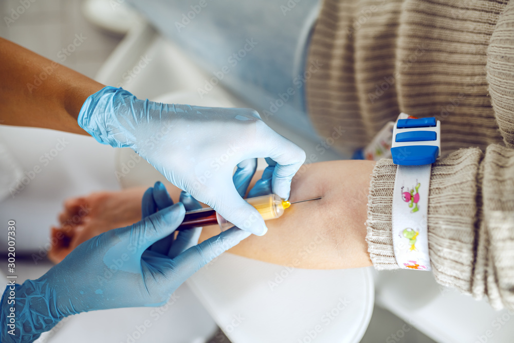 Close up of lab assistant with sterile rubber gloves taking blood sample from patient. Close up of lab assistant with sterile rubber gloves taking blood sample from patient.