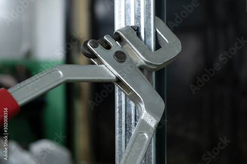 A woman with beautiful nails uses a special tool-a prosekatel, for fastening a metal profile for drywall