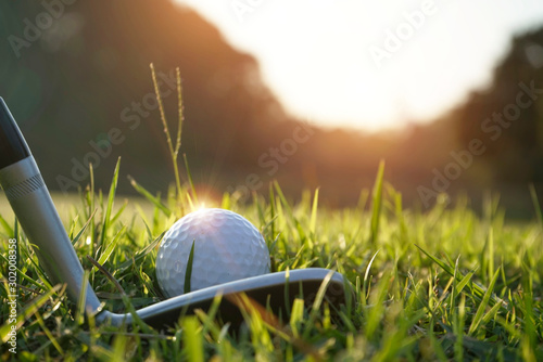 Blurred golf club and golf ball close up in grass field with sunset. Golf ball close up in golf coures at Thailand
