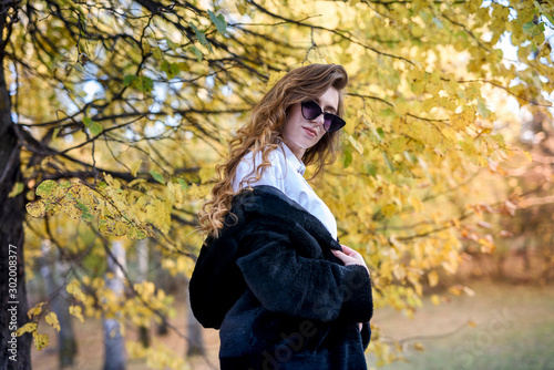 Beautiful young woman in a fur coat in the magical autumn forest.