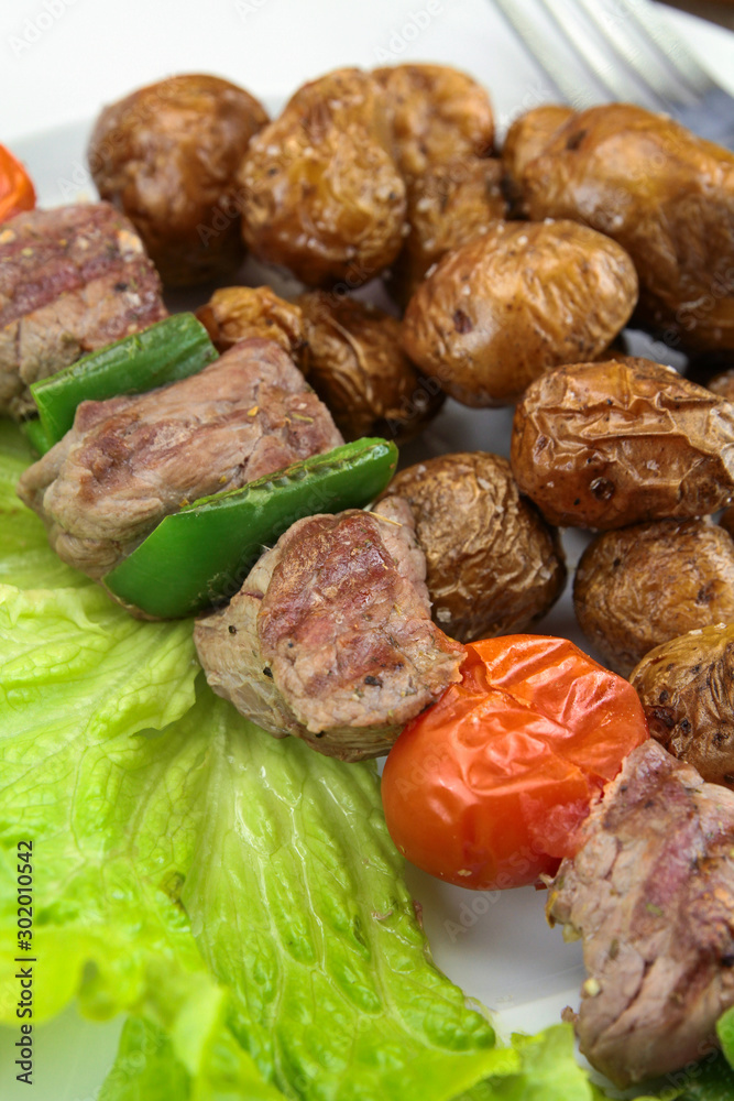 grilled potatoes and beef skewer on a plate