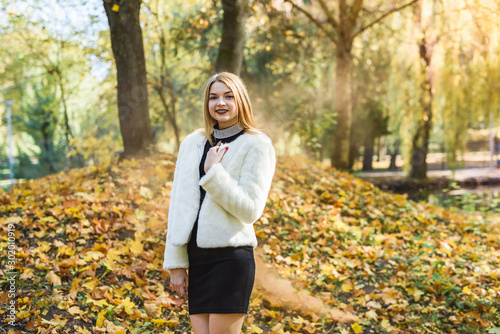 Fashion dresses woman in fur coat and dress posing in autumn park © RomanR