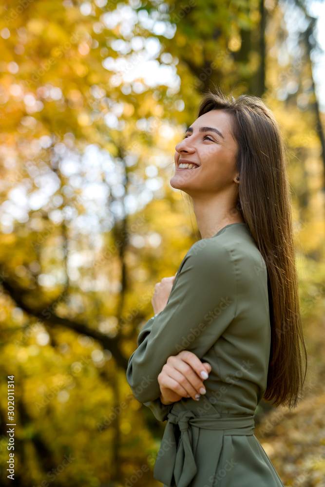 Portrait of brunette woman in green dress posing in autumn park Portrait of brunette woman in green dress posing in autumn park