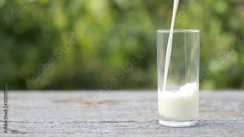 Fresh milk is poured into a glass on a wooden table. Tasty healthy food. A glass of milk. Diet