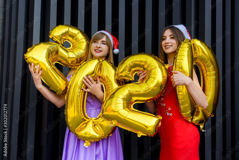 Happy young women with golden 2020 balloons. New Year celebration Happy young women with golden 2020 balloons. New Year celebration