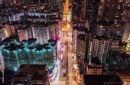 Car  taxi  and bus traffic on road intersection at night in Hong Kong downtown district  drone aerial top view. Street commuter  Asia city life  or public transportation concept