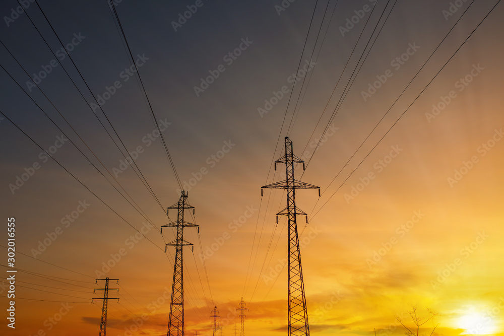 Power lines at sunset, sun rays. High voltage tower against the sky. Energetics