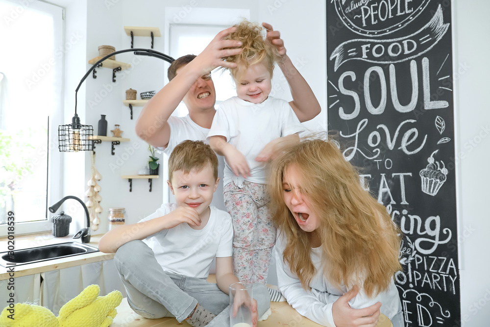 Happy family at home spending time together and playing. Crazy family heaving fun in dright kitchen room.
