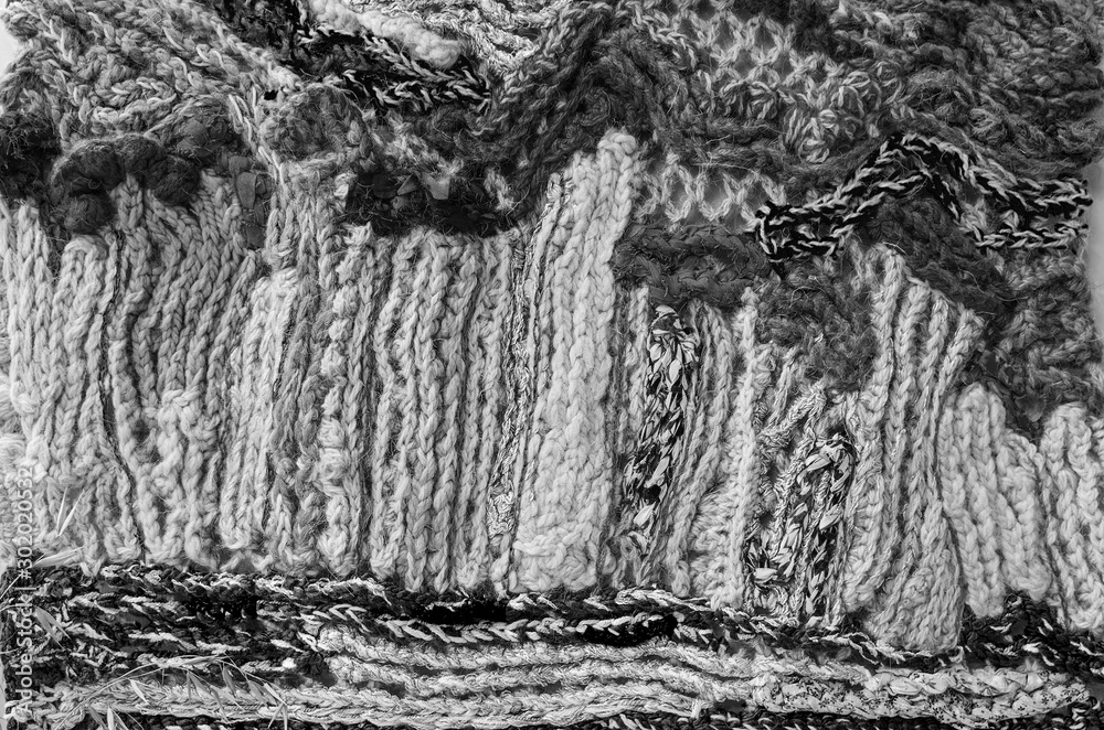 Fragment of the panel, connected from heterogeneous and multi-colored woolen threads, non-repeatable pattern, close-up, black-and-white image.