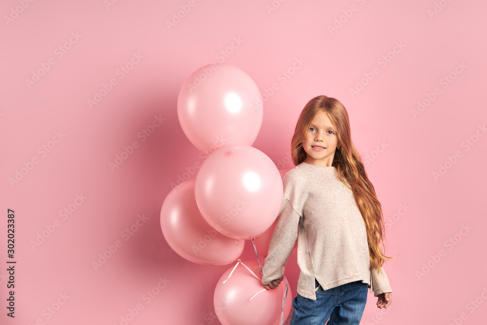 Portrait of funny caucasian kid girl with pink air balloons, long hair and big beautiful eyes, wearing white blouse and jeans. Portrait of funny caucasian kid girl with pink air balloons, long hair and big beautiful eyes, wearing white blouse and jeans.