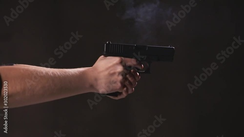 Woman shooting a handgun with recoil.  gun in slow motion. The flame comes out of the mouth of the gun. Indoor black background