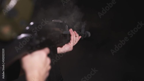 Woman shoots with assault rifle Saiga carbine in slow motion. Cartridge comes out of the gun. CloseUp photo