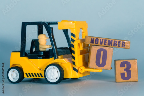 november 3rd. Day 3 of month, Construction or warehouse calendar. Yellow toy forklift load wood cubes with date. Work planning and time management. autumn month, day of the year concept
