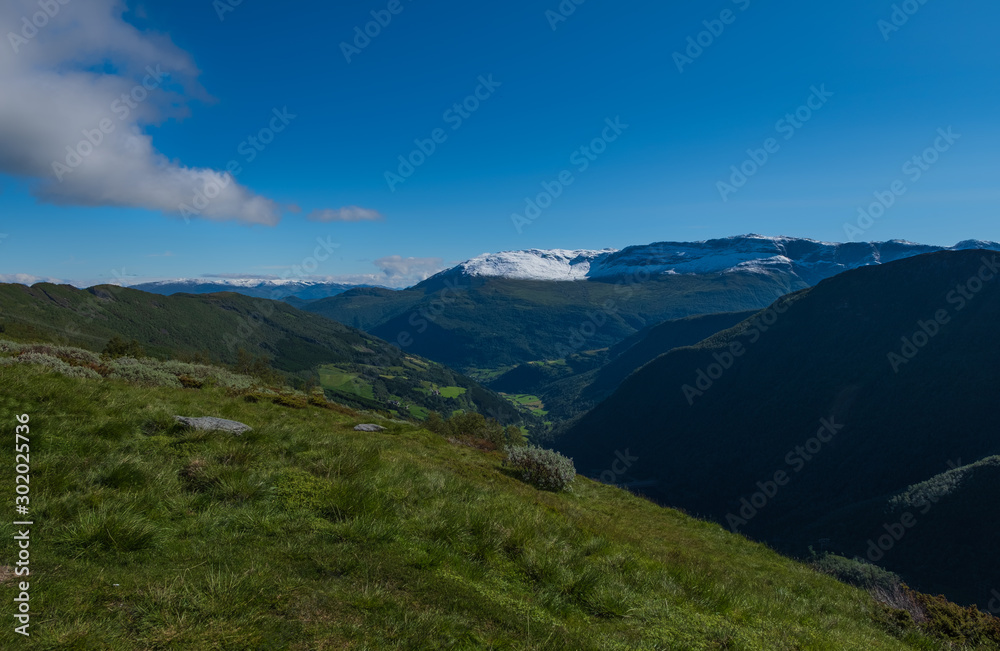 Through the Vikafjell a pass road to Vik is located in the kommunes Hordaland and Sogne og Fjordane. Mountains with summer snow on background. July 2019