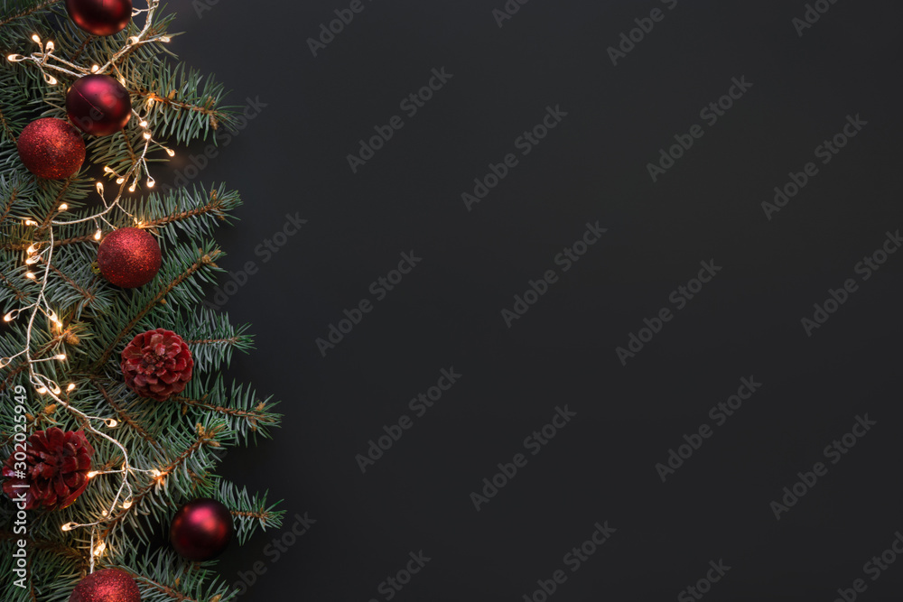 Christmas frame with fir branches, red balls, garland on black background. Space for text, view from above, flat lay.