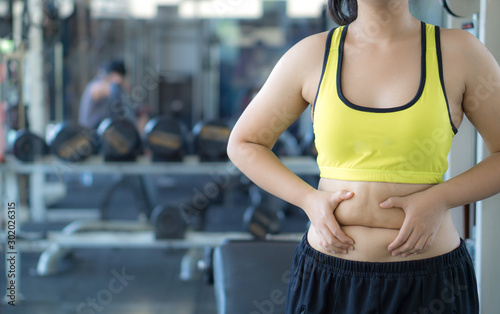 Fototapeta Naklejka Na Ścianę i Meble -  Close up woman holding excessive fat belly. Woman overweight abdomen. Woman diet lifestyle concept reduce belly and shape up healthy stomach muscle. Weight loss, slim body, healthy lifestyle concept.