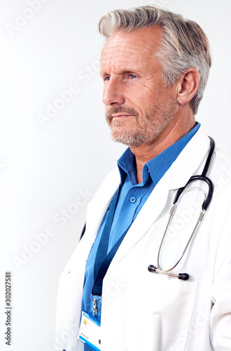 Profile Studio Shot Of Mature Male Doctor Wearing White Coat And Stethoscope On White Background