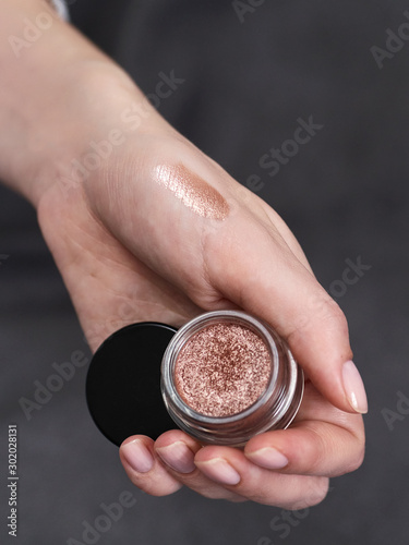 Woman's beauty blogger hands holding bottles and tubes spa professional hi-end cosmetics applies sample tone color on skin with copyspace