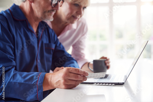 Mature Couple At Home Looking Up Information About Medication Online Using Laptop