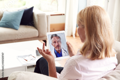 Mature Woman Having Online Consultation With Doctor At Home On Digital Tablet