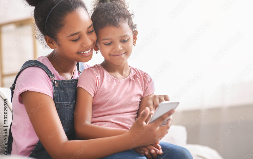 African sisters watching funny videos online on mobile phone African sisters watching funny videos online on mobile phone