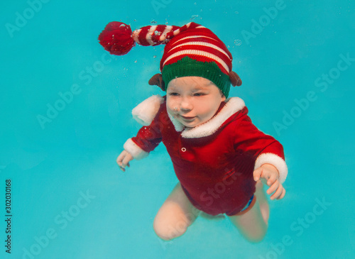 Caucasian infant underwater in new year and christmas suit in the swimming pool