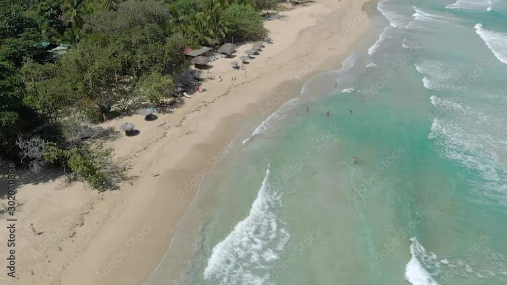 Tilt-up view of a small beach club on a pristine beach in Panama with waves breaking over shallow sand. Tilt-up view of a small beach club on a pristine beach in Panama with waves breaking over shallow sand.