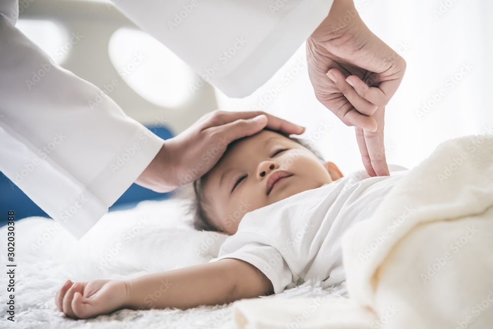 The doctor is using two fingers to press down in the middle of the baby's chest, which is CPR in the case that the child stops breating, to health care and insurance concept. The doctor is using two fingers to press down in the middle of the baby's chest, which is CPR in the case that the child stops breating, to health care and insurance concept.