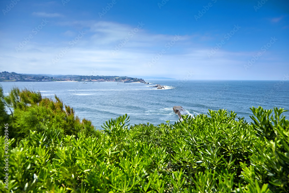 Landscape with green hill, dike and view of coastal french town, Basque Country, Atlantic coast, France. Beautiful french landmark at sunny summer day with blue sky