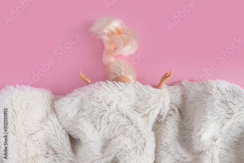 Fotografia, Obraz The dolls head and hands are visible from under the synthetic white fur