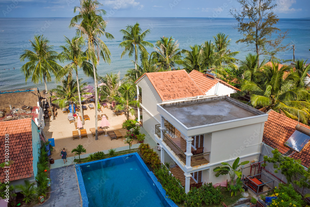 Phu Quoc island, Vietnam - March 30, 2019: hotel with a pool on the coastline of the Indian Ocean, high palm trees, sea horizon