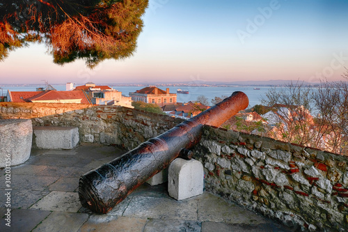  old cannon on high stone walls castle of Saint George Castle  the City of Lisbon in Portugal   evening during sunset photo