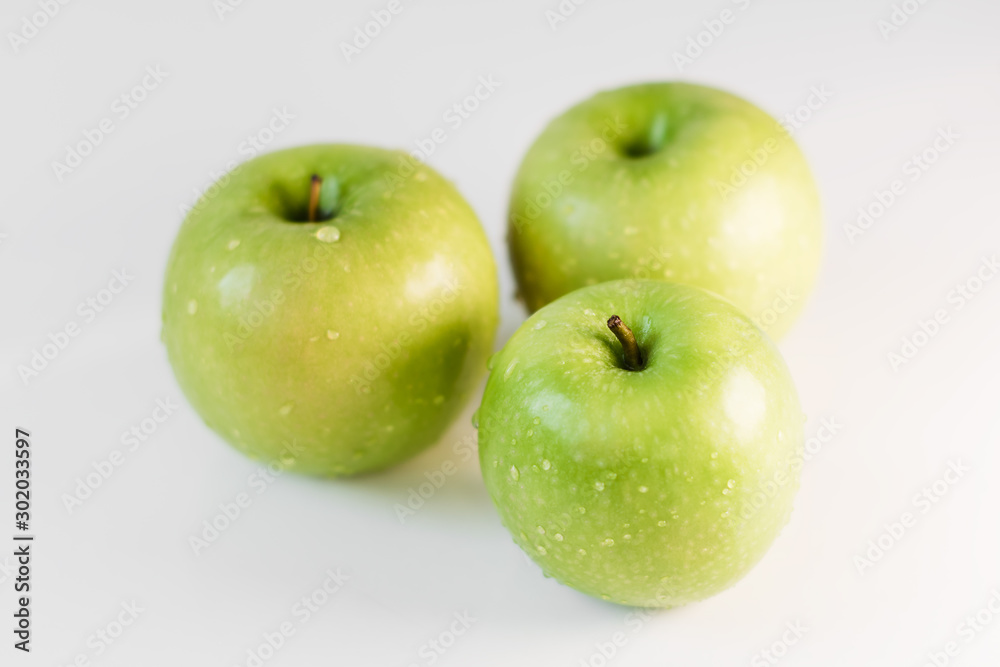 Fresh green apples with water droplets on a white glossy kitchen table. Tasty bright juicy fruits. Healthy eating. Isolated object. Fresh green apples with water droplets on a white glossy kitchen table. Tasty bright juicy fruits. Healthy eating. Isolated object.